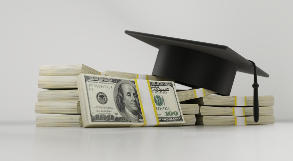 Graduation hat on a pile of dollars money representing the best way to save money for kids to go to college