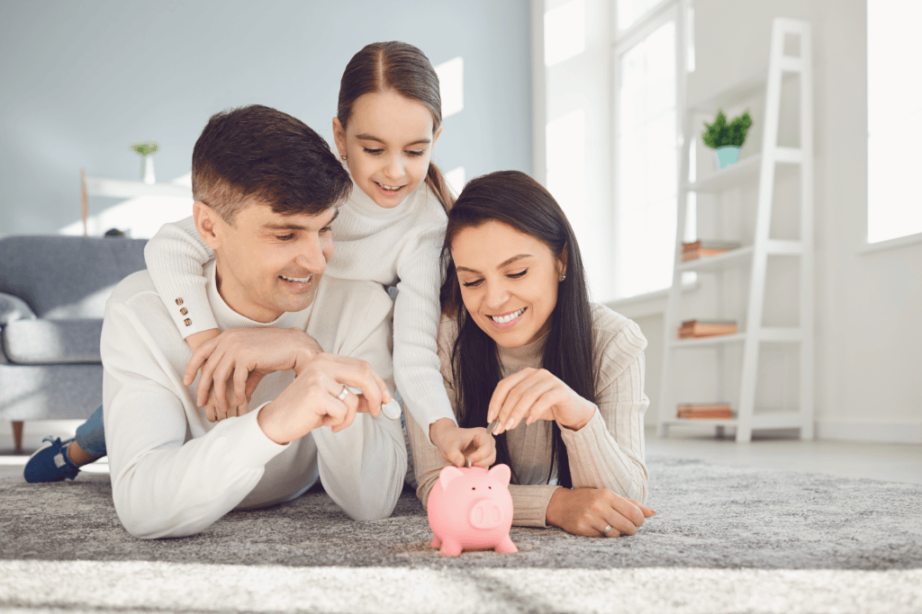 Happy family saving money in a piggy bank representing the Practical Strategies that Parents can use to teach kids about abundance