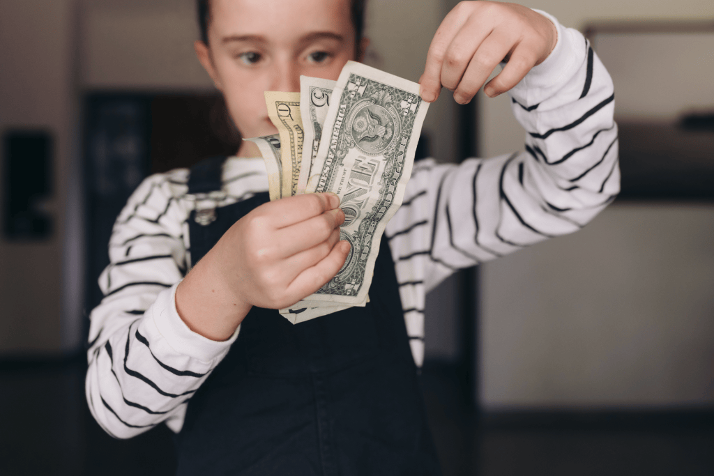 irl holding dollar bills in her hand representing the role of parents to rewire children’s neural pathways toward optimism, flexibility, and smart risk-taking.