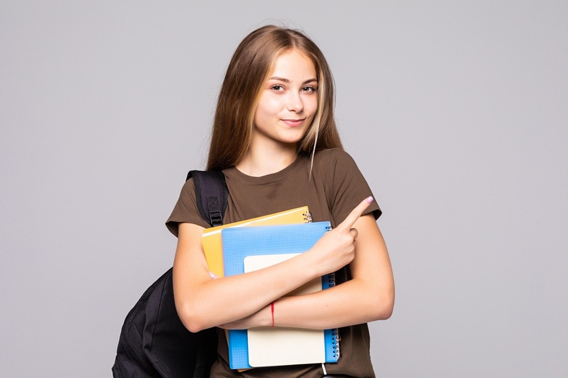 happy teenager with a backpack and notebooks in her hands